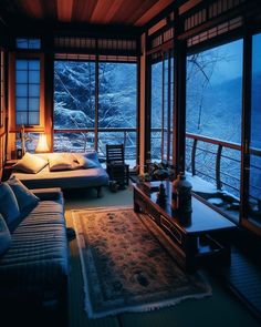 a living room filled with furniture and large windows overlooking the snow covered mountain range at night