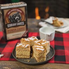 there are pieces of cake on the plate next to some coffee and a box of kohluak cakes