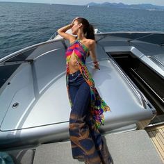 a woman standing on the back of a boat in the ocean with her arms behind her head