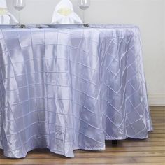 a table with two glasses on it and a silver cloth draped over the table top