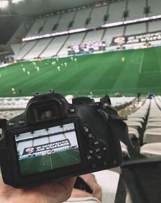 a person holding up a camera in front of a stadium