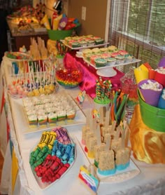 a table filled with lots of different types of desserts and candies on sticks