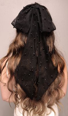 the back of a woman's head wearing a black hat with pearls on it