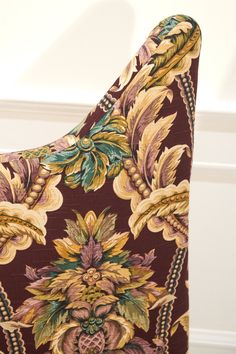 a close up of a chair with a flower pattern on the back and seat cushion