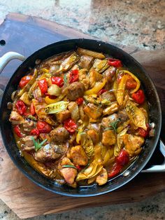 a pan filled with meat and vegetables on top of a wooden table