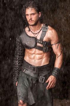 a shirtless man with no shirt on standing in the rain wearing armor and chains