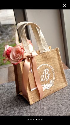 a brown bag with a pink rose on it sitting on a table next to a window