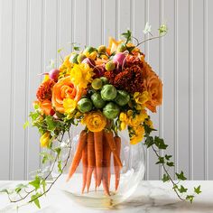 a vase filled with carrots and flowers on top of a table