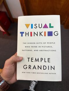 a person holding up a book about visual thinking