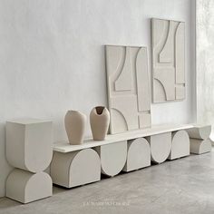 three white vases sitting on top of a shelf next to two mirrors and a wall