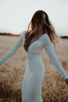 a woman in a white dress standing in a wheat field