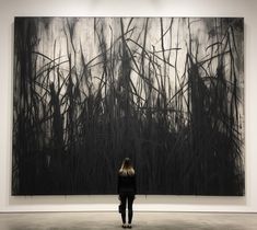 a woman standing in front of a large black and white painting