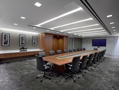 an empty conference room with chairs and a large table in front of a flat screen tv