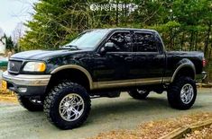 a black pickup truck parked on the side of a road in front of some trees