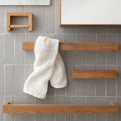 a white towel hanging on a wooden shelf next to a mirror and other bathroom accessories