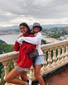 two women standing on a balcony with their arms around each other