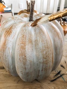 a white painted pumpkin sitting on top of a wooden table next to a brush and some other items