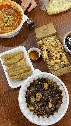 there are many different foods on the table and one is in a box with noodles