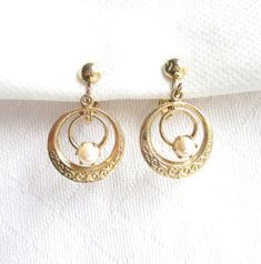 These pearl bead and gold hoop earrings feature a dangling double circle form with a scroll like metal stamped detailing.  Each earring face measures 1 1/4" tall by 3/4" wide.  The gold metal round scroll hoop and dangling center pearl swing and sway with any movement.  The face of each clip fixture is a gold metal ball.  The pearls look and feel to be genuine, set in deep prong settings.  The clip back fixtures are working properly.  There are no hallmarks and this pair is in very good vintage condition.    Comes carefully gift boxed for safe and secure delivery.  I ship daily, everyday, except on Sundays, so your parcel may be on its way to you today!  Shipping upgrades are available; priority and express via USPS domestic and international shipping.  All of my items listed are VINTAGE i Metal Ball, La Face, Vintage Clip, Jewelry Earrings Hoops, Gold Hoop, Gold Hoop Earrings, Metal Stamping, Estate Jewelry, Pearl Beads