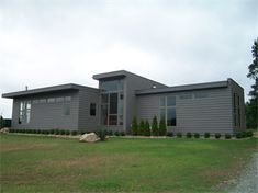 a large gray house sitting on top of a lush green field