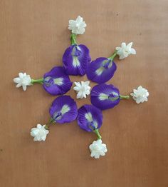 purple and white flowers are arranged in the shape of a snowflake on a wooden surface