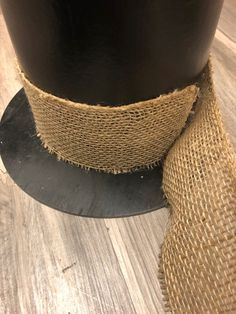 there is a roll of burlap on the floor next to a black vase