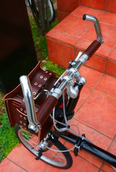 a close up of a bike on a brick walkway with grass and red tiles in the background