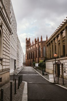 an empty street in front of some buildings with tall towers on each side and a light pole at the end