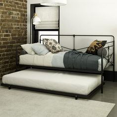 a bed with a metal frame sitting next to a brick wall