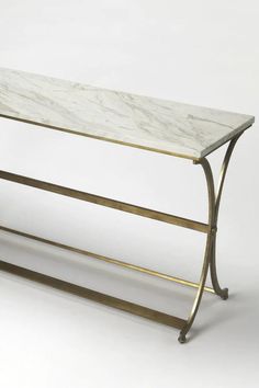 a marble topped console table with gold metal legs and a white marble top, against a plain background