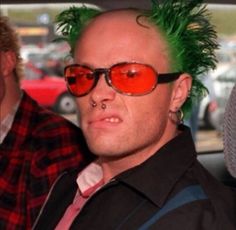 a man with green hair wearing red sunglasses