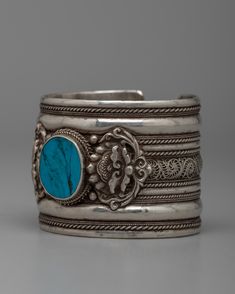 Tibetan Turuqoise Bracelet About The Bracelet: Discover the distinctive appeal of this handcrafted bracelet made of Tibetan turquoise set on a silver. This eye-catching piece has a vivid turquoise stone inlaid in the center to draw attention to its magnificent blue-green hues, which are believed to symbolize peace, healing, and protection. The polished silver wonderfully sets the turquoise, bringing forth its inherent beauty and elevating the bracelet to the status of a noteworthy piece of jewel Traditional Blue Bracelets With Natural Stones, Turquoise Jewelry With Intricate Design, Spiritual Turquoise Cuff Bracelet With Natural Stones, Turquoise Cuff Bracelet With Natural Stones, Handmade Turquoise Spiritual Bangle, Handmade Spiritual Turquoise Bangle, Traditional Turquoise Round Bracelets, Traditional Turquoise Round Bracelet, Handmade Turquoise Sterling Silver Bracelet Gift