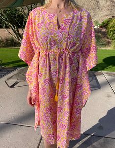 Our beautiful block-print coverups are printed by hand by textile artisans in Jaipur India. The "Mirabelle" short coverup is made in a lightweight organic cotton and features a pink floral and paisley design on our classic kaftan shape with notch neckline, drawstring detail to adjust the fit, cotton tassel trim and side slits for an easy-breezy look. Wear it as a dress over your favourite swimwear to keep cool and covered up or as comfy lounge wear. You may find some small marks on the fabric, these are tiny dye droplets and a normal feature of the wood block printing process signifying the handmade nature of these products. SIZE AND FIT INFORMATION One size fits all: UK dress size 10-16 (US sizes 6-12) Model is 5' 8" UK dress size 12 (US size 8) and wears one size Length: 95cm (37.5 inche Pink Block Print, Tassel Outfit, Cotton Kaftan Dress, Comfy Lounge Wear, Maxi Kaftan, Comfy Lounge, Cotton Kaftan, Women's Cover Up, Keep Cool