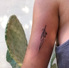 a woman's arm with a tattoo on it and a plant in the background