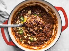 a ladle full of chili and meat in a pot