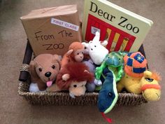 stuffed animals and books in a basket on the floor next to a cardboard box that says dear zoo