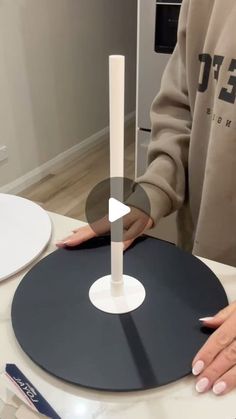 a person standing next to a table with a record on it and a candle in the middle