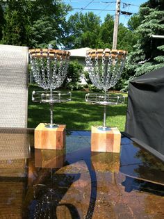 two glass vases sitting on top of a table in the middle of a yard