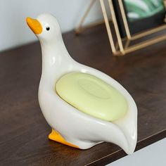 a duck shaped soap dish sitting on top of a wooden table next to a mirror