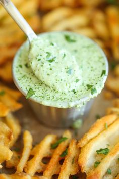 there is a small bowl filled with dip next to some french fries