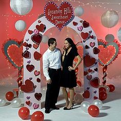 a man and woman standing in front of an arch with hearts on it for valentine's day