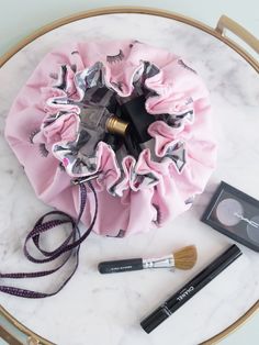 the contents of a make up bag are displayed on a marble table with a brush