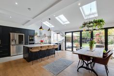 an open kitchen and dining room area with skylights above the countertop, hardwood flooring, and black cabinetry