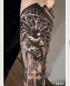 a man's arm with an angel and cross tattoo on it