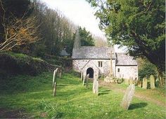 an old stone church in the middle of a green field with tombstones and trees