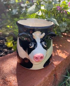 a black and white cow vase sitting on top of a brick wall