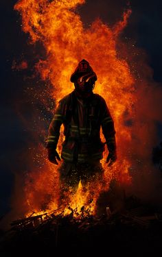 a firefighter standing in front of a blazing bush