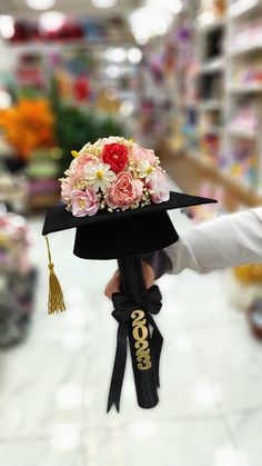 a person holding a graduation hat with flowers on it in the middle of a store aisle