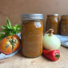 there is a jar with some food in it next to tomatoes and peppers on the table