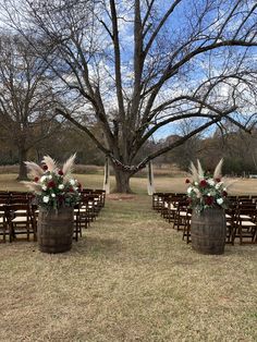 an outdoor ceremony setup with chairs and flowers in buckets on the grass, surrounded by trees